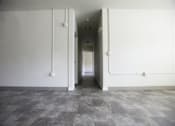 Thumbnail 13 of 39 - A long hallway with white walls and tile flooring.