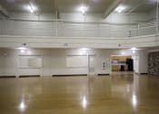 Thumbnail 24 of 39 - A spacious room with wooden floors and white walls.