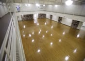 Thumbnail 26 of 39 - A large empty dance studio with wooden floors and mirrors on the walls.