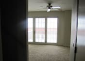 Thumbnail 11 of 12 - A room with a ceiling fan and a door leading to a balcony.