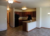 Thumbnail 8 of 17 - A kitchen with brown cabinets and black appliances.