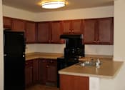 Thumbnail 9 of 17 - A kitchen with black appliances and wooden cabinets.