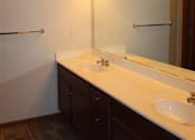 Thumbnail 17 of 17 - A bathroom with a white counter top and brown cabinets.
