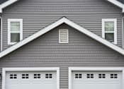 Thumbnail 3 of 17 - A house with two white garage doors.