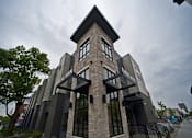 Thumbnail 13 of 17 - A modern building with a stone facade and large windows.
