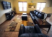 Thumbnail 5 of 17 - A black leather couch sits in a living room with a rug and a coffee table.
