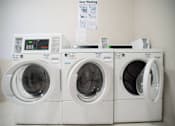 Thumbnail 10 of 21 - Three white washing machines are lined up in a row.