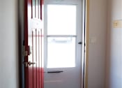 Thumbnail 12 of 21 - A red door is open to a room with a window.