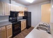 Thumbnail 17 of 21 - A kitchen with black appliances and wooden cabinets.