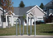 Thumbnail 3 of 21 - A metal bike rack sits on a sidewalk in front of a house.