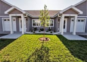 Thumbnail 5 of 21 - A tree is planted in a small garden in front of a house.