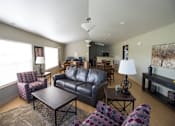 Thumbnail 7 of 21 - A living room with a black leather couch and a wooden coffee table.