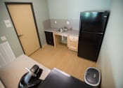 Thumbnail 9 of 21 - A small kitchen with a black fridge and a sink.
