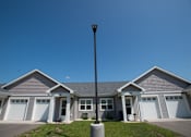 Thumbnail 2 of 13 - A house with a grey roof and white garage doors.