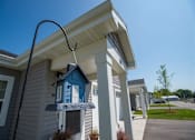Thumbnail 3 of 13 - A blue birdhouse is hanging from a pole in front of a house.
