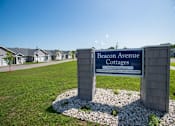 Thumbnail 4 of 13 - A sign for Beacon Avenue Cottages in front of a row of houses.