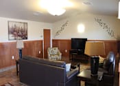 Thumbnail 13 of 15 - A living room with a couch, chair, and television.