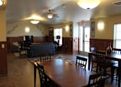 Thumbnail 14 of 15 - A living room with a black couch and a wooden dining table.