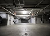 Thumbnail 10 of 21 - A car is parked in a dimly lit parking garage.