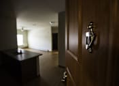 Thumbnail 5 of 21 - A brown door with a silver handle and a room with a table and a window.