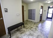 Thumbnail 11 of 21 - A hallway with a bench and a door with a window.