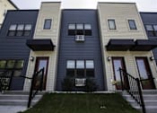 Thumbnail 7 of 21 - A row of townhouses with black railings and steps leading to the front doors.