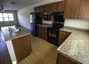 Thumbnail 6 of 21 - A kitchen with wooden cabinets and black appliances.