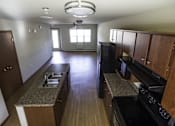 Thumbnail 15 of 21 - A kitchen with wooden cabinets and a black stove top oven.