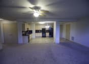 Thumbnail 17 of 22 - A spacious living room with a ceiling fan and a kitchen area in the background.
