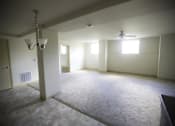 Thumbnail 18 of 22 - A spacious room with a carpeted floor, a ceiling fan, and a chandelier.