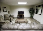 Thumbnail 19 of 22 - A living room with a grey couch and a television.