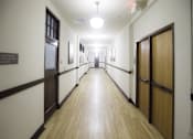 Thumbnail 11 of 27 - A long hallway with doors on both sides and a sign on the wall.