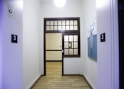 Thumbnail 13 of 27 - A hallway with a door and a wall-mounted light fixture.