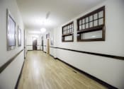 Thumbnail 14 of 27 - A long hallway with wood floors and white walls.