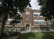 Thumbnail 17 of 27 - A large red brick building with a flag pole in front.