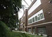 Thumbnail 18 of 27 - A building with a green lawn in front.