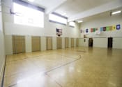 Thumbnail 2 of 27 - A gym with a wooden floor and a basketball hoop.
