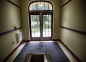 Thumbnail 5 of 27 - A hallway with a large arched doorway leading to a grassy area.