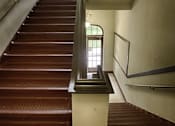 Thumbnail 6 of 27 - A staircase with a metal handrail and wooden steps.