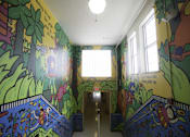 Thumbnail 7 of 27 - A hallway with a mural on the walls and a light hanging from the ceiling.