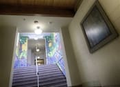Thumbnail 8 of 27 - A staircase with a light on the top and a painting on the wall.