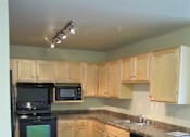 Thumbnail 11 of 18 - A kitchen with black appliances and brown tiled floors.