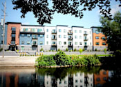Thumbnail 3 of 18 - A row of modern apartment buildings are reflected in the water.