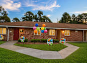 Thumbnail 2 of 4 - A house with a driveway and a sign that says "Welcome to Sunshine Elementary School".