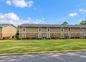 Thumbnail 5 of 11 - Apartment complex with a grassy front yard and a clear blue sky.