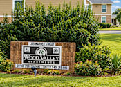 Thumbnail 3 of 11 - A sign for Wood Valley Apartments is in front of a building.