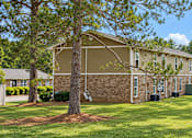 Thumbnail 2 of 11 - A tree stands in front of a building with a green lawn in front of it.