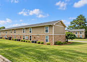 Thumbnail 10 of 11 - A long brick building with a green lawn in front.