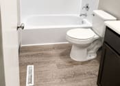 Thumbnail 4 of 5 - A white toilet sits next to a bathtub in a bathroom.