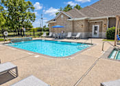 Thumbnail 9 of 10 - A pool with a blue umbrella and chairs around it.